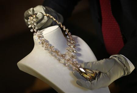 Rose gold necklace with a 407 carat yellow diamond is removed from a stand during a media event in Singapore