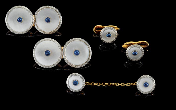 Set di gioielli da uomo, composto da due gemelli, due bottoni da camicia e un bottone da colletto con la catena, in oro giallo e bianco con zaffiri cabochon e madreperla. Stima: 750 - 900 euro