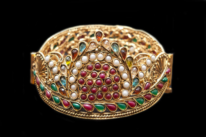 Bracciale indiano in metallo dorato, con vetri e perle. Prezzo: 145 euro
