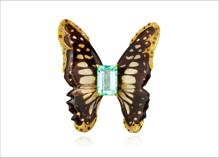Spilla a forma di farfalla con al centro uno smeraldo, con oro zaffiri e diamanti che circondano le ali