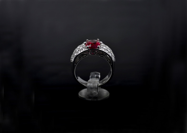 Anello a fascia con rubino ovale e pavé di diamanti. Microsculture di delfini collegano la galleria con il pavé 
